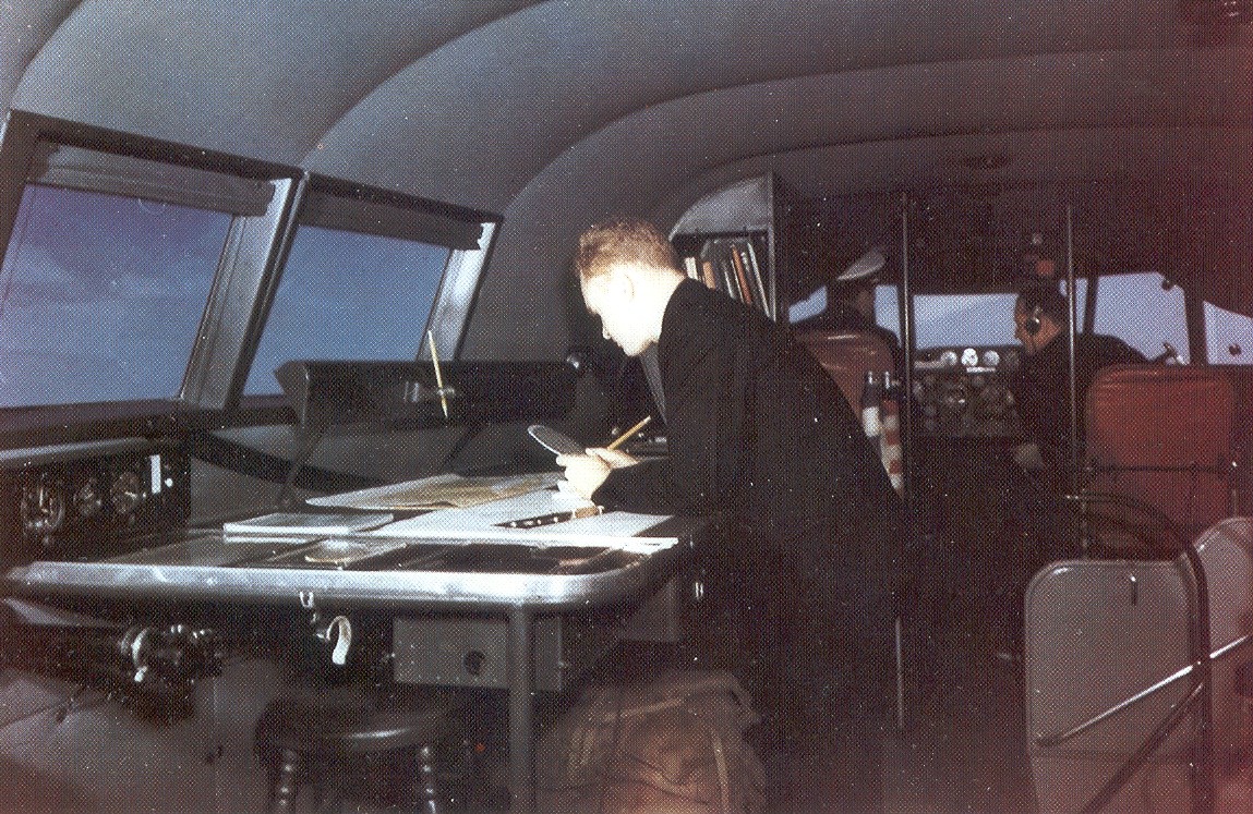 Boeing B314 Navigator at work on plotting table.  Pilot and co-pilot left and right behind the navigators right shoulder.